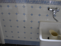 Achtkantige witte wandtegel in combinatie met blauwe plinttegel, blauwe sluittegel en blauwe sierstrip.